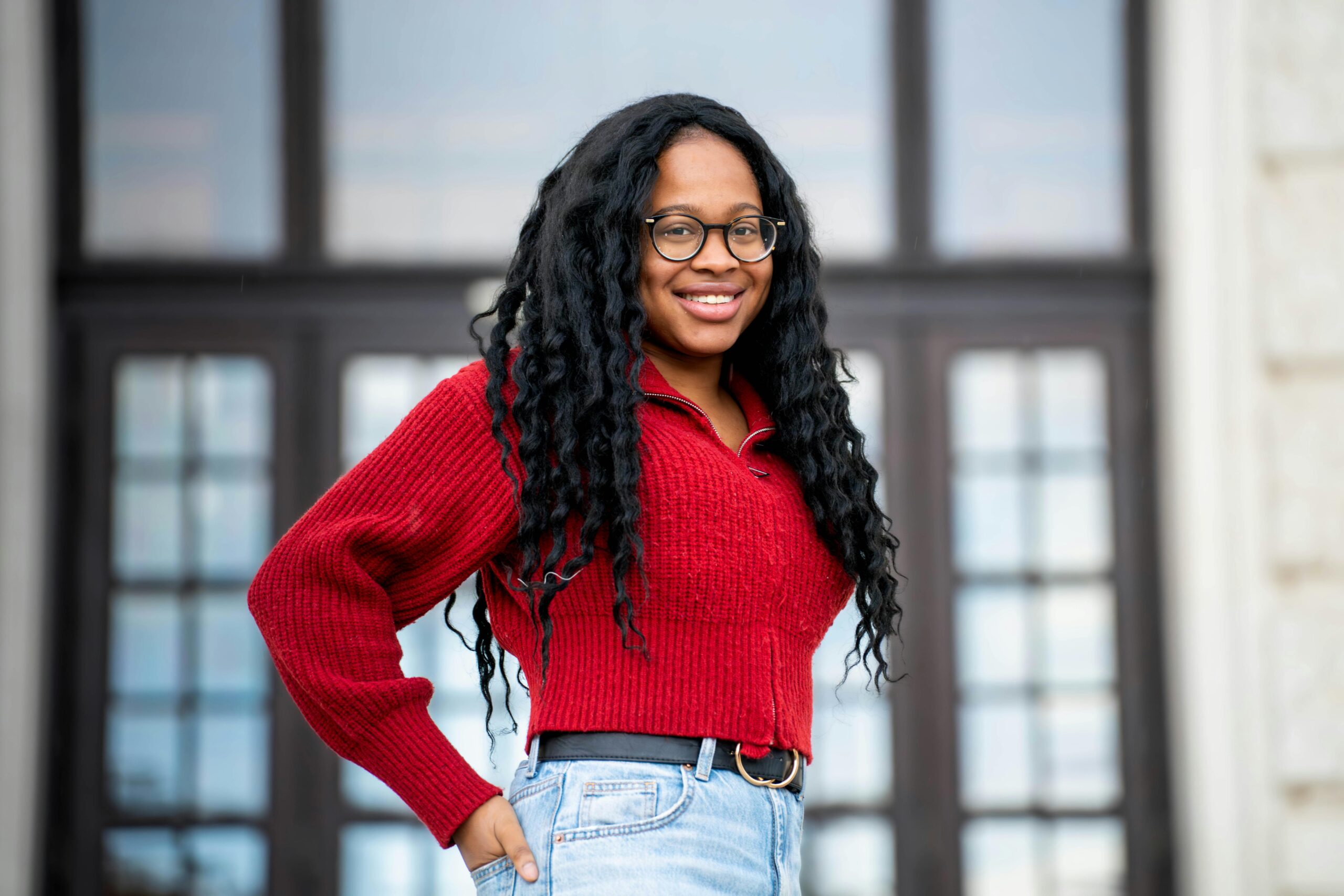 Portrait of a smiling woman in a red sweater standing outdoors in Vienna, Austria.