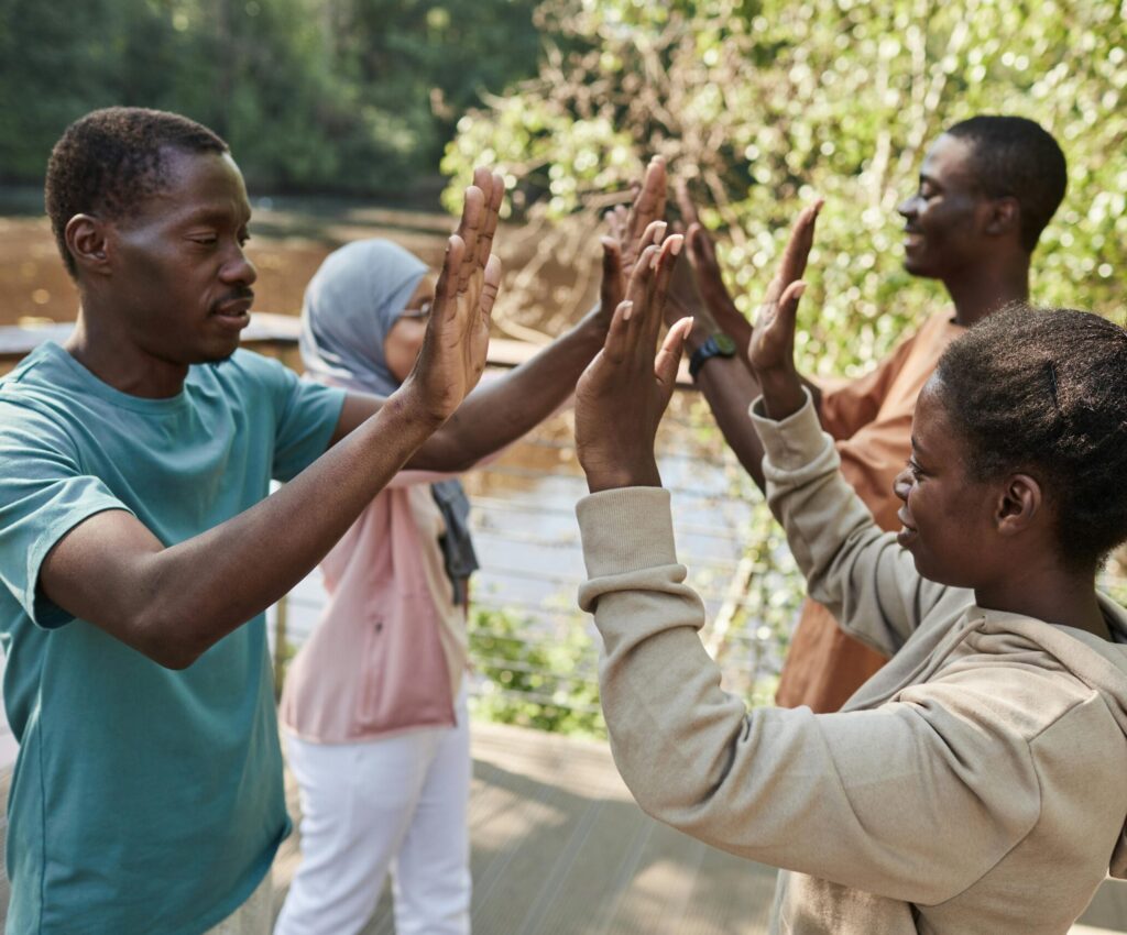 A group of friends enjoying a high-five outdoors, symbolizing camaraderie and joy.