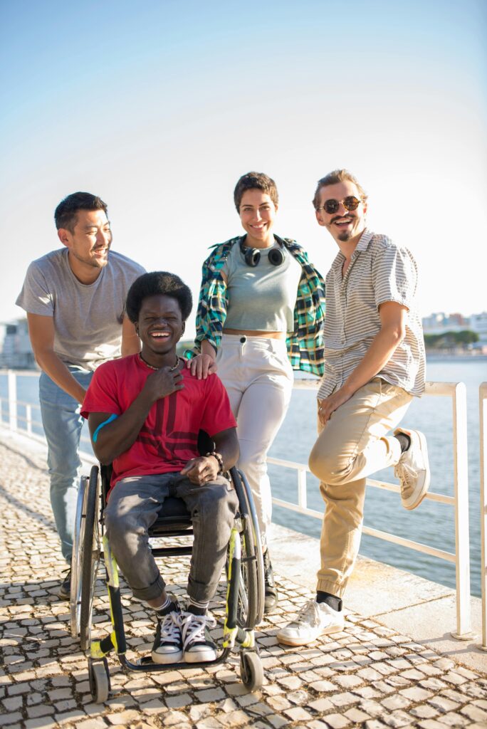 A diverse group of young friends share laughter by the riverside, highlighting friendship and inclusivity.